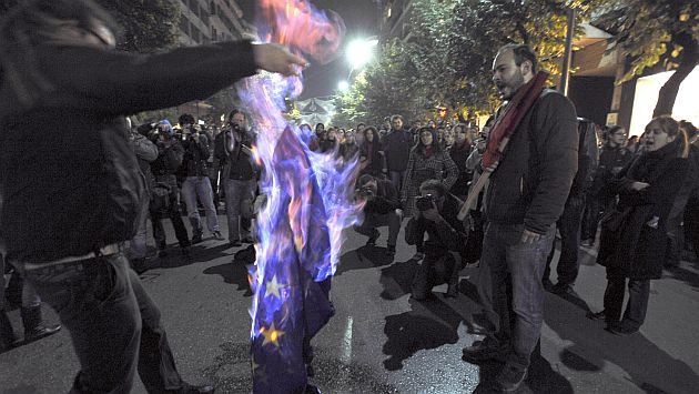 Manifestantes queman una bandera de la UE en protesta por su manejo de la crisis. (AP)