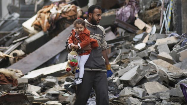 Hombre palestino carga a su hija entre los escombros que dejó un bombardeo israelí en Gaza. (Reuters)