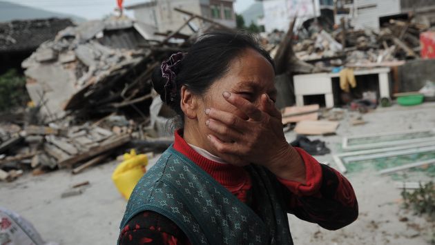 DESCONSUELO. Una mujer llora al ver destruida su vivienda y al no poder ubicar a sus familiares. (AP)