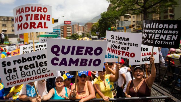DEMANDA. Ciudadanos venezolanos con carteles exigen un cambio de dirección en un país en crisis. (EFE)