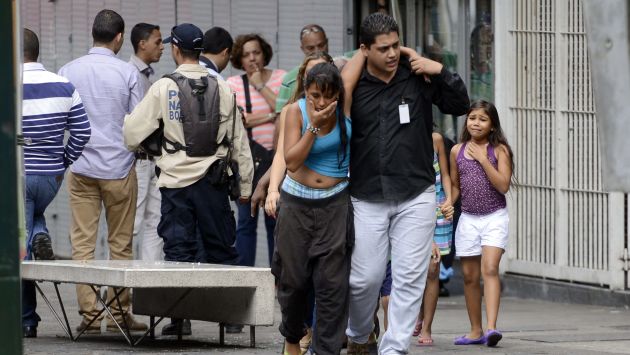 Venezolanos abandonan un edificio tras un tiroteo. (AFP)