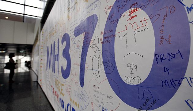 Una pasajera observa un mural con mensajes para los desaparecidos del avión de Malaysia Airlines. (EFE)