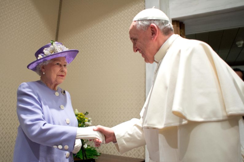 Reina Isabel II, vestida de lila y un clásico sombrero del mismo color, fue recibida junto con su esposo en un salón anexo de la moderna sala de audiencias Pablo VI y no en el suntuoso palacio apostólico. (AFP)