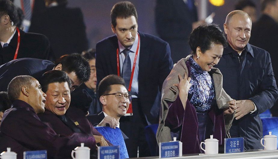 Fue un gesto amable en una noche fría. Vladimir Putin colocó una manta sobre los hombros de la esposa del presidente chino Xi Jinping. (AP)