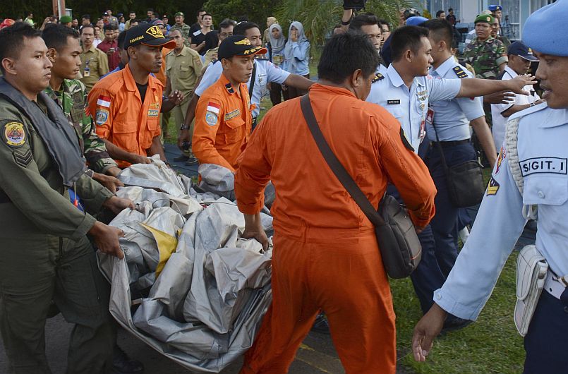 Autoridades cargan algunas partes recuperadas del avión de AirAsia. (AP)