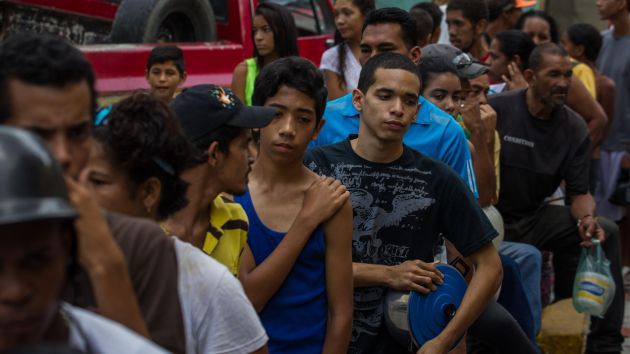 Grupo de jóvenes esperan para recibir ración de comida en Caracas. (EFE)